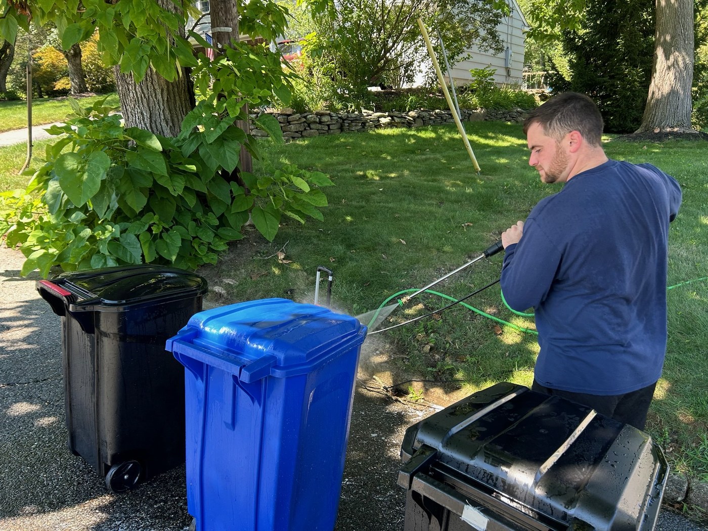 Robert power-washing a trash can in the yard