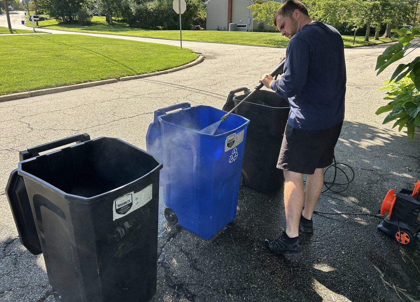 Power washer cleaning a trash can