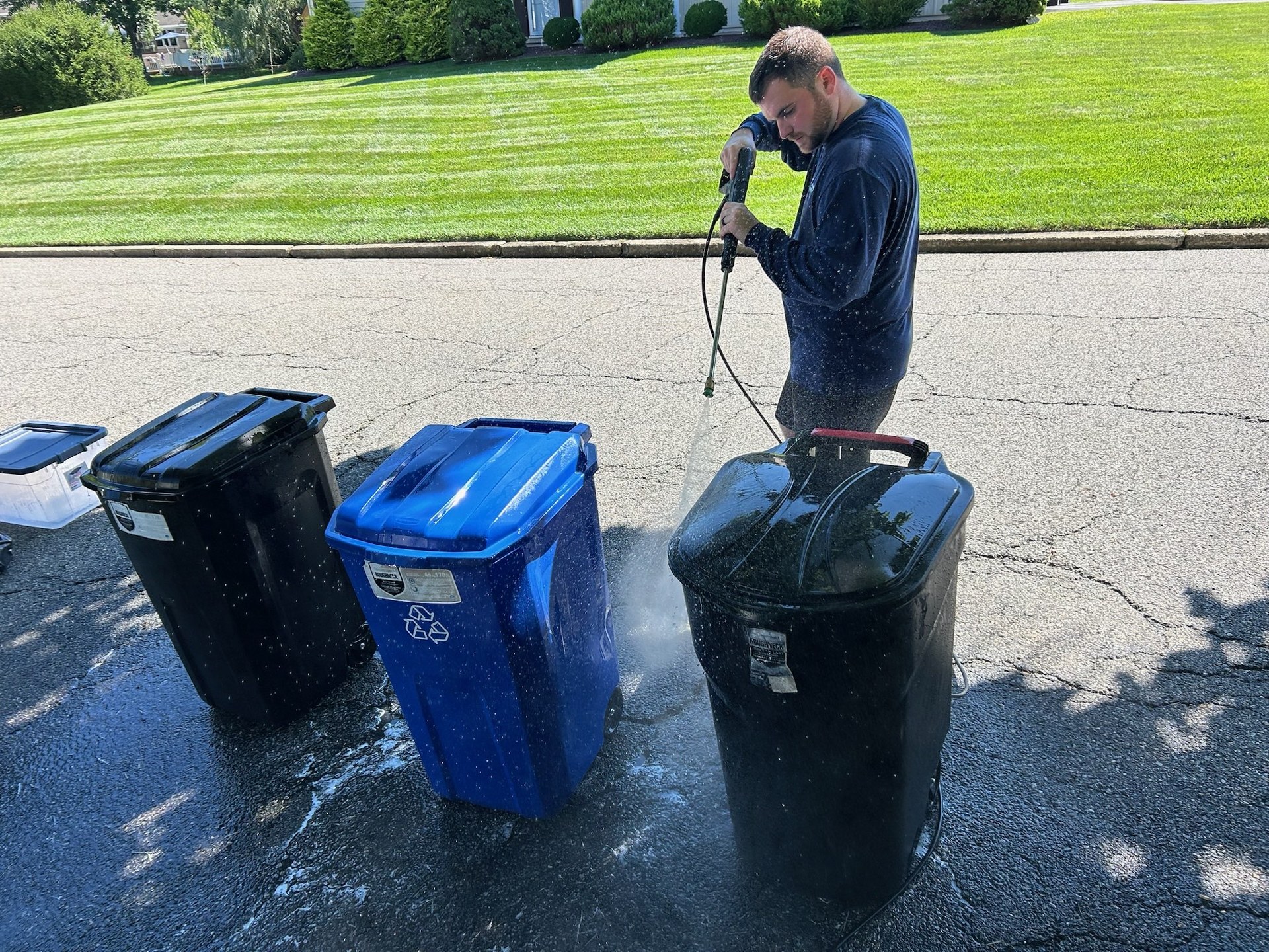 Robert power-washing a trash can curbside