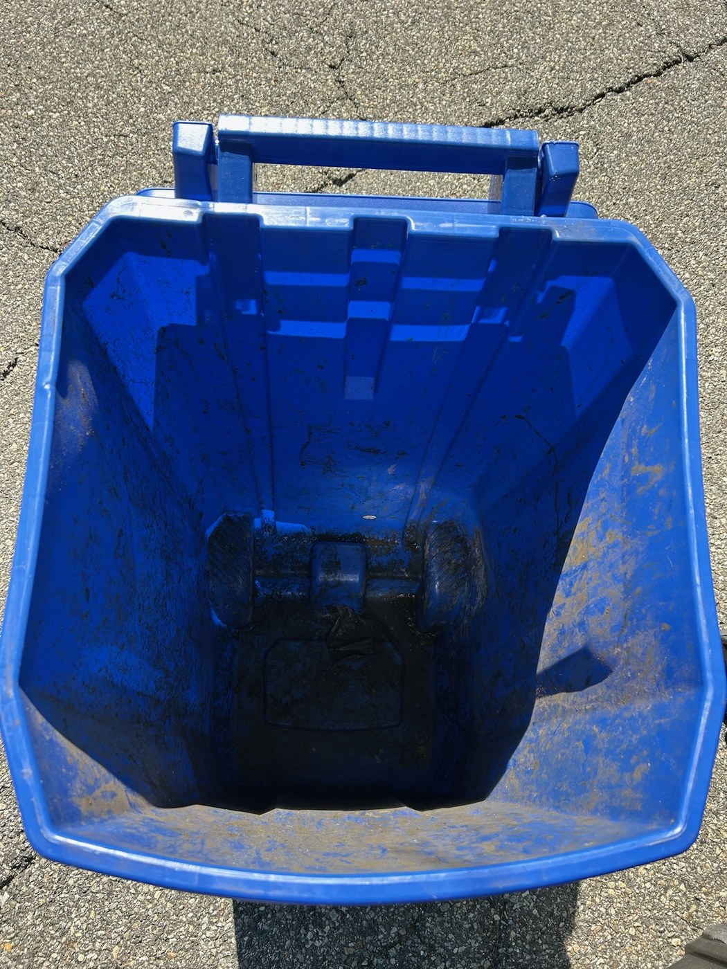 A recycling bin before cleaning, caked with grime